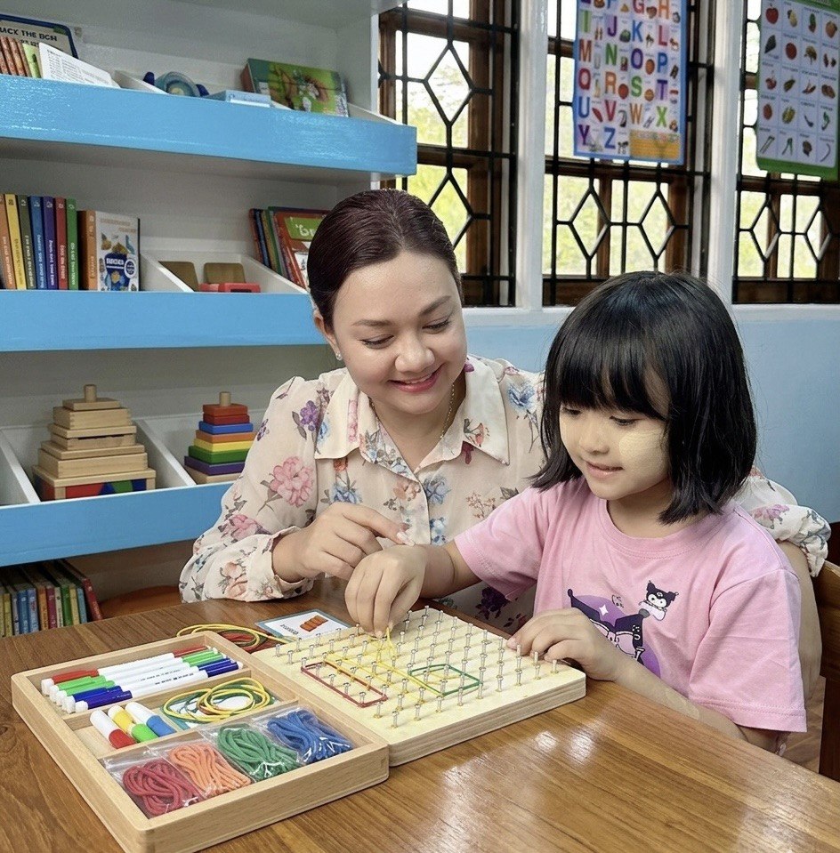 Teacher helping a child with a hands-on learning board