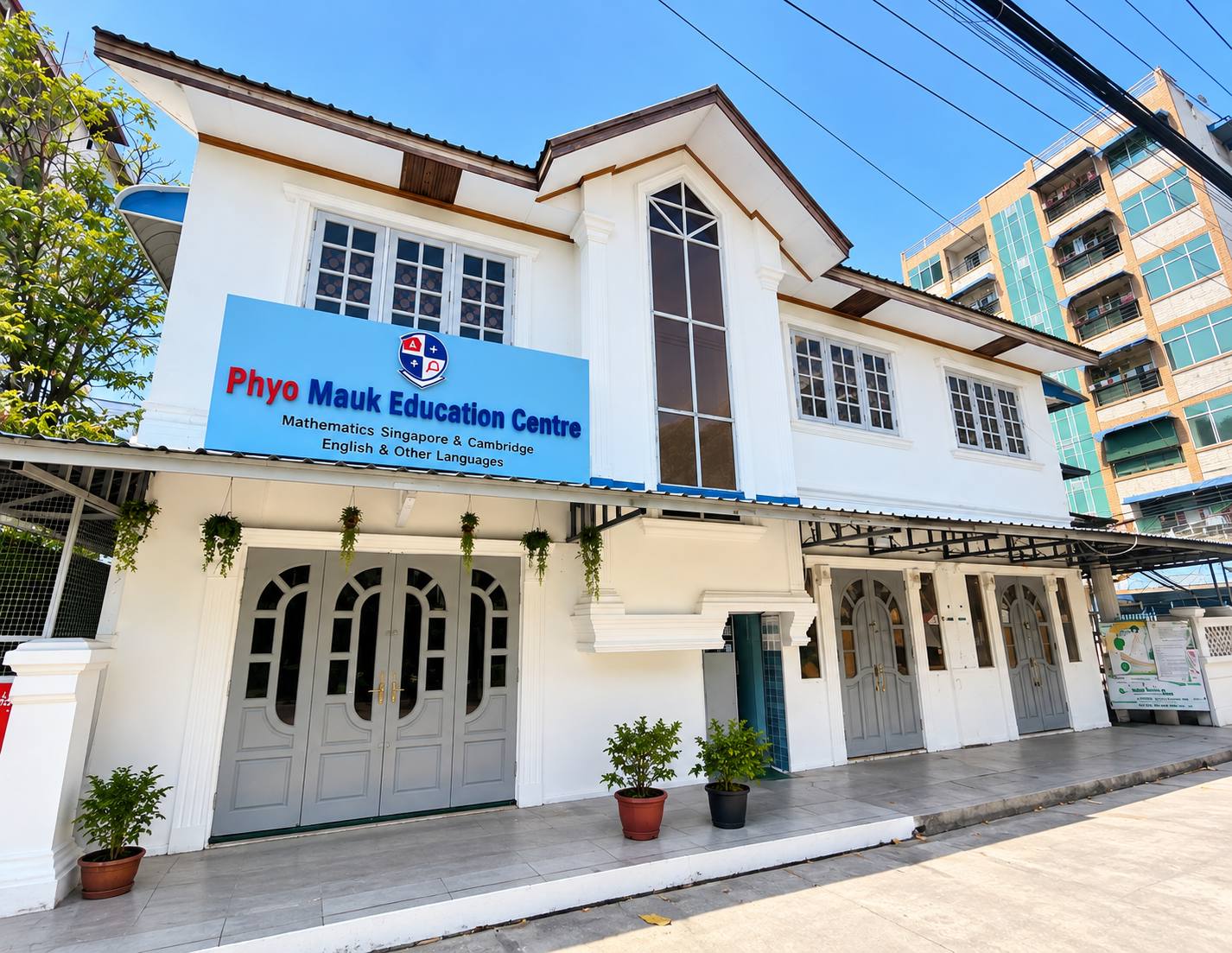 Phyo Mauk Education Centre's white building, blue school sign and street entrance